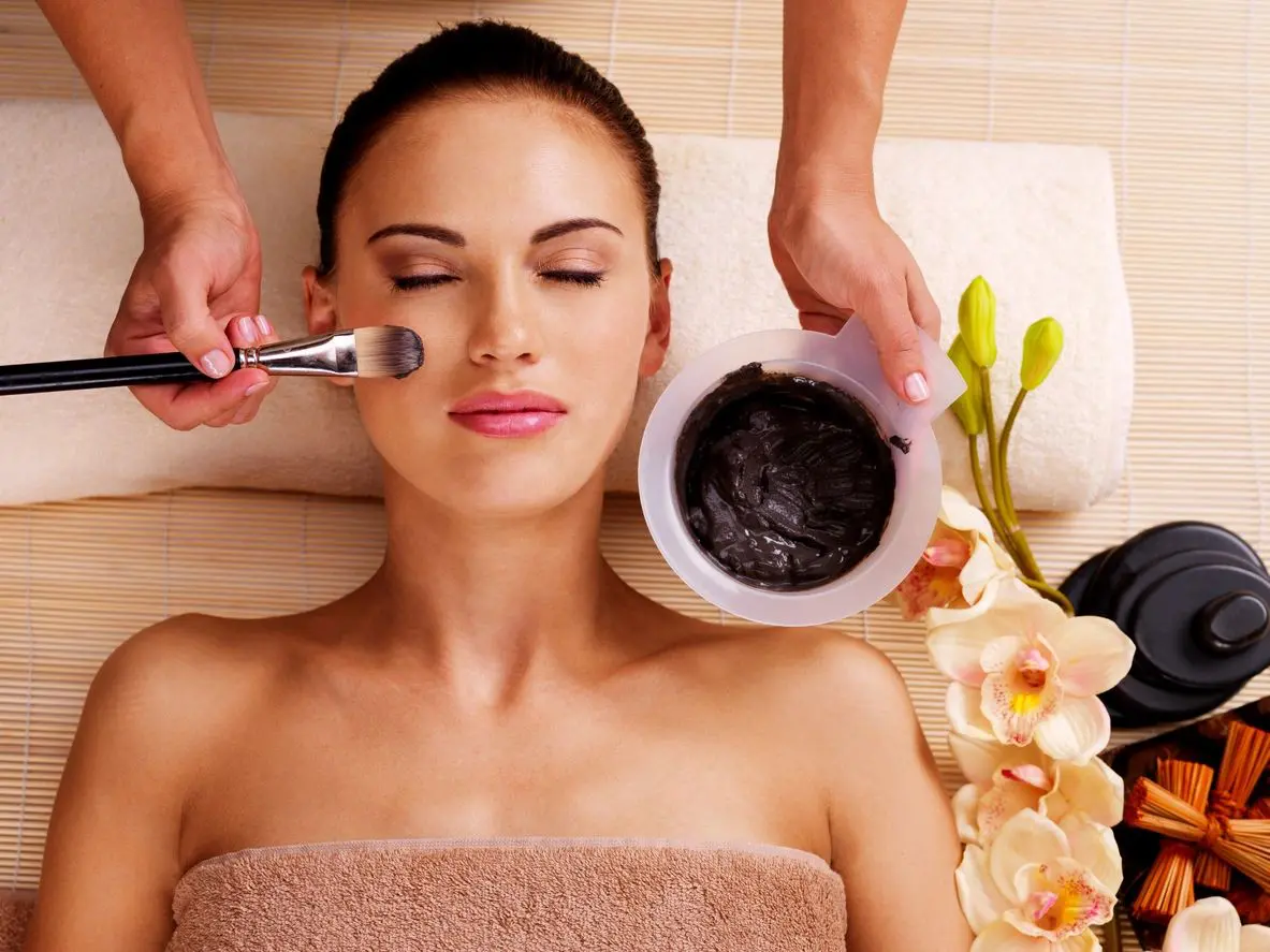 A woman getting her face washed with clay