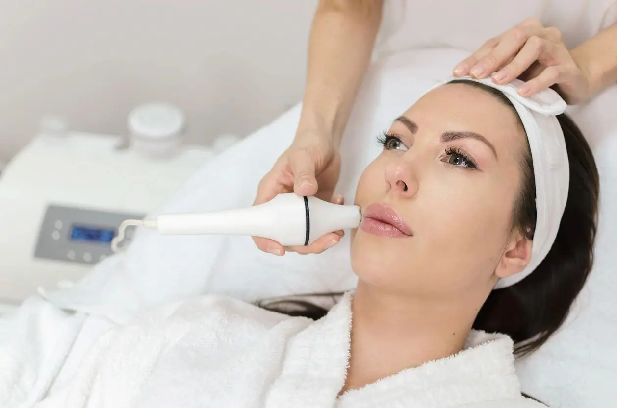 A woman getting her face cleaned with an electric device.