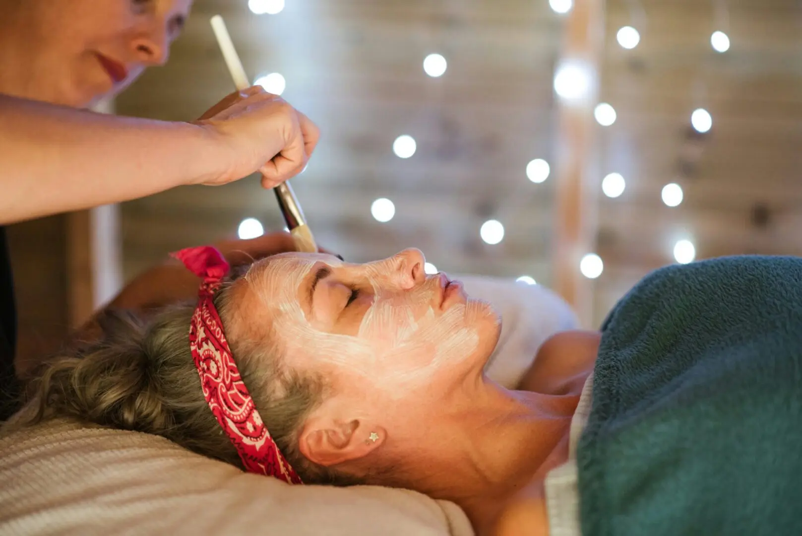 A woman getting her face painted with makeup.