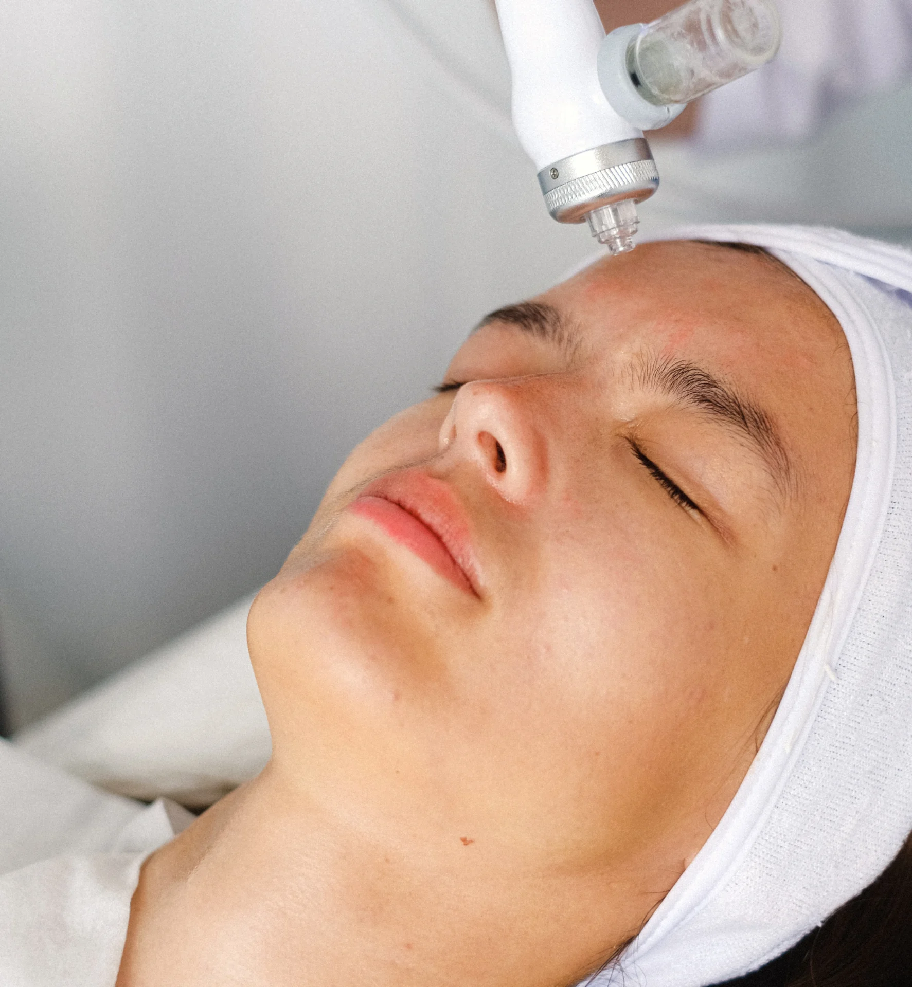 A woman getting her face cleaned by an electric device.