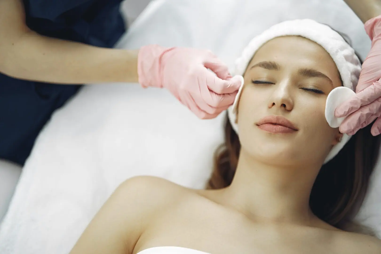 A woman getting her face cleaned by a person.