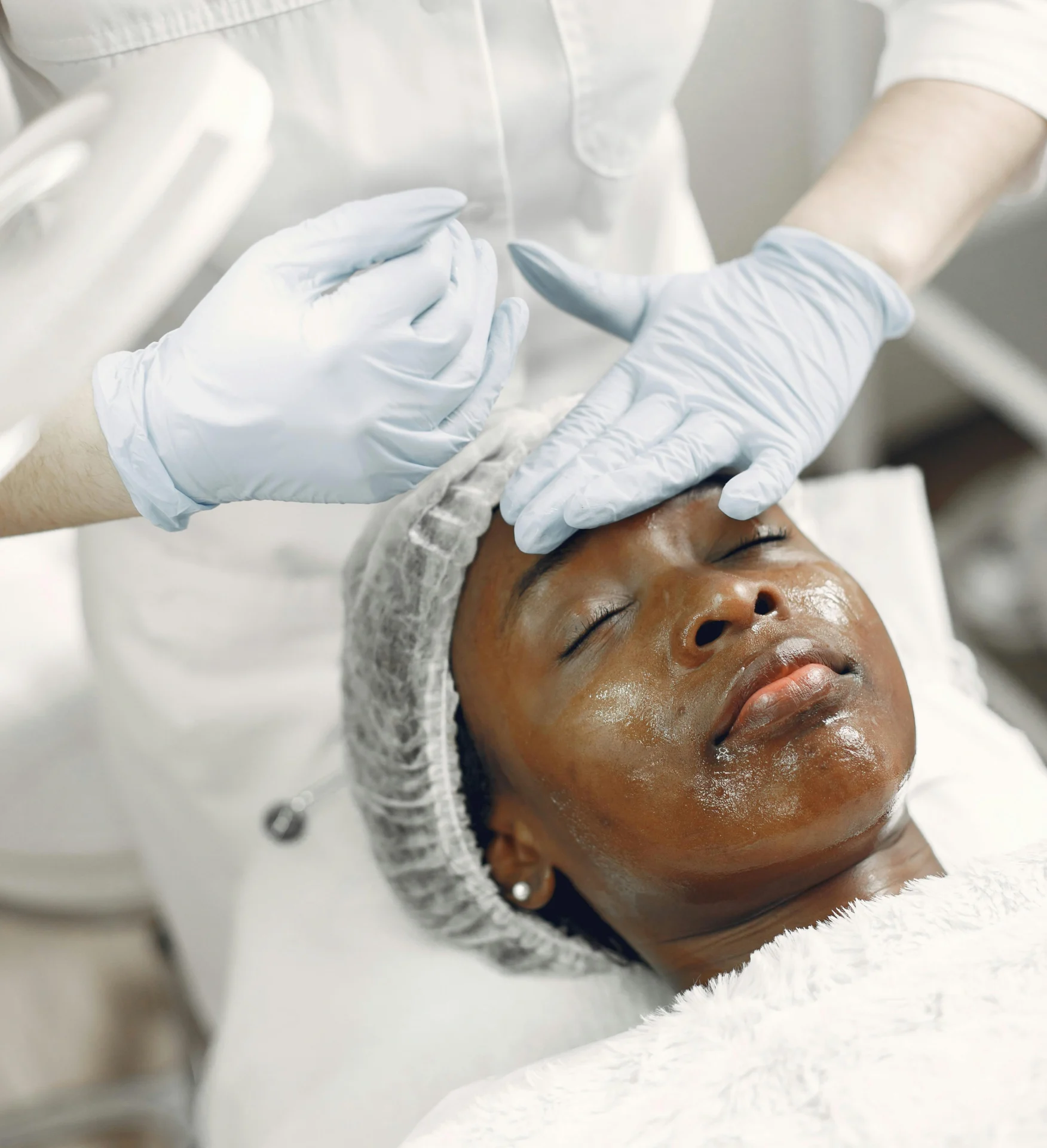 A woman is getting her face waxed by a cosmetologist.