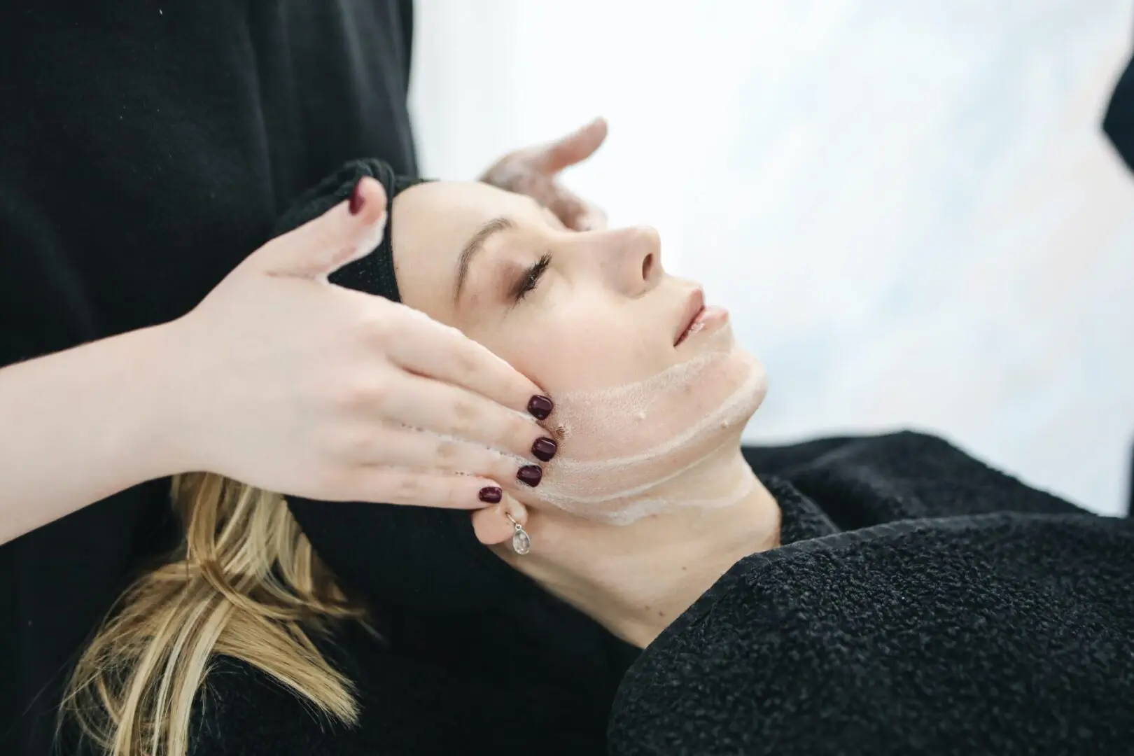 A woman getting her face washed by a person.