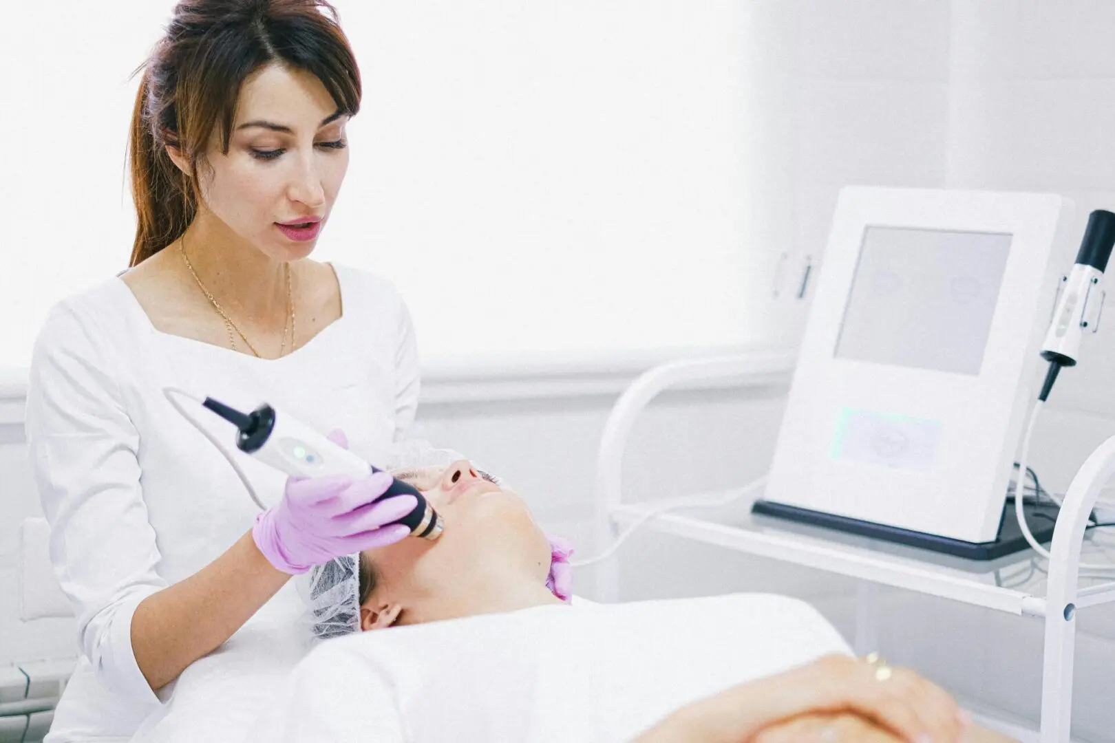 A woman is using an electric device on the face of a man.